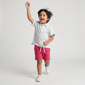 Kid wearing Kiggle Classic Polo in Snow with raspberry terry shorts